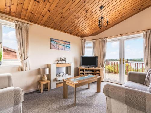 a living room with a couch and a tv at Chalet Loch Side Lodge 5 by Interhome in Kinross