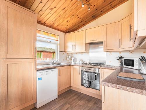 a kitchen with white appliances and wooden cabinets at Chalet Loch Side Lodge 5 by Interhome in Kinross