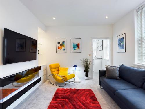 a living room with a blue couch and a tv at No 3 at Upton Cross House, Chester in Backford