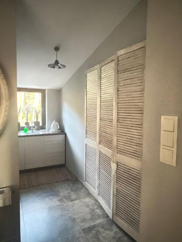 a room with a kitchen with wooden doors and a window at Natura Mierzei 30 - pokoje przy plaży in Krynica Morska