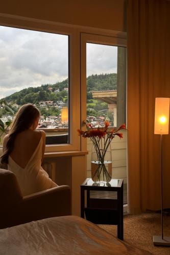a woman sitting in a chair looking out of a window at LuCA Hotel in Bodenmais