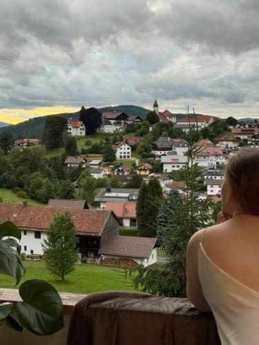 a woman sitting on a balcony looking at a city at LuCA Hotel in Bodenmais