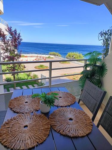 une table avec quatre parasols sur un balcon avec la plage dans l'établissement Saint Raphaël lieu paradisiaque, à Saint-Raphaël