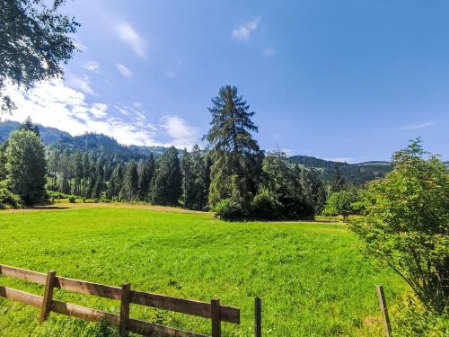 a field with a wooden fence in a green field at Chalet Altavista by Interhome in Ziano di Fiemme