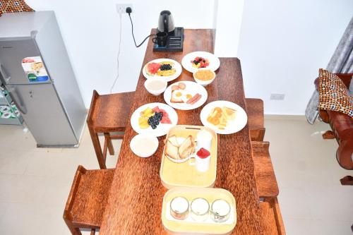 a wooden table with plates of food on it at Michamvi Holiday Homes in Michamvi