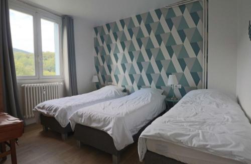 a bedroom with two beds and a window at Les Agapanthes in La Bourboule