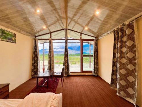 a room with a table and a large window at Green Land Resort, Katpanah Lake, Skardu, Gilgit Baltistan in Skardu