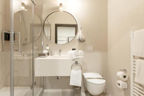 a white bathroom with a sink and a mirror at Aparthotel Lavilo Main Square in Graz