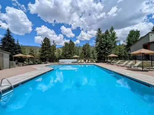 a large blue swimming pool with chairs and umbrellas at Flying Dutchman 1155 by SummitCove Lodging in Keystone