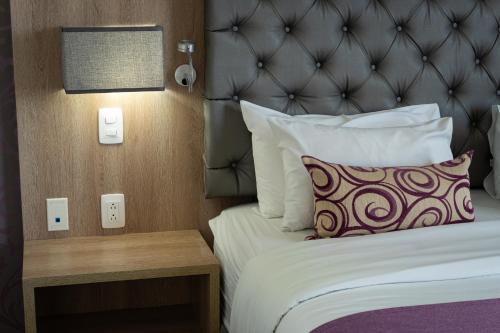 a hotel room with a bed with a headboard and a pillow at Hotel Roseliere Bucaramanga in Bucaramanga