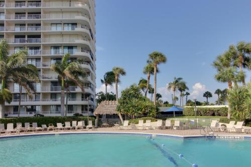 a swimming pool in front of a building with palm trees at The Breezy Perch in Marco Island