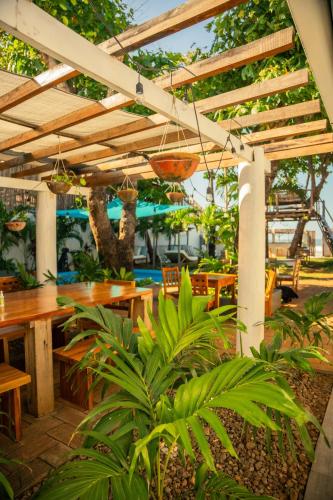 un patio con mesas, sillas y una pérgola en JAKES ON THE BEACH, en Las Peñitas