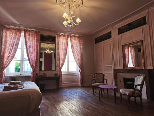 a bedroom with a bed and two chairs and a chandelier at Chez Diane in Saint-Amand-Montrond