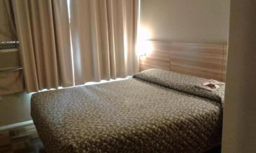 a bedroom with a bed with a light on it at Vicz Palace Hotel in Curitiba