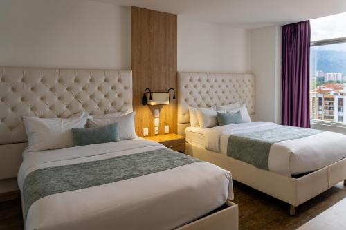 a hotel room with two beds and a window at Hotel Roseliere Bucaramanga in Bucaramanga