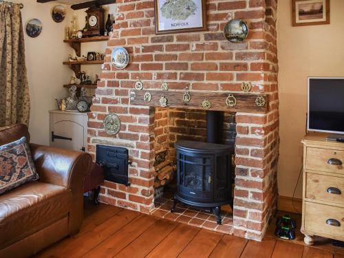 a living room with a brick fireplace with a stove at Honeysuckle Cottage in Great Yarmouth