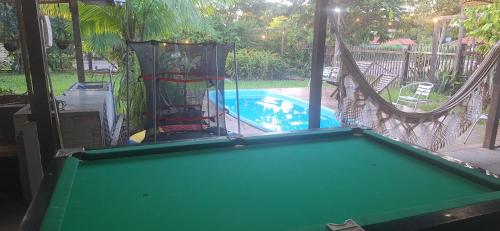 a pool table with a hammock next to a swimming pool at Espaço Sairé - 8 minutos da Praia in Alter do Chao