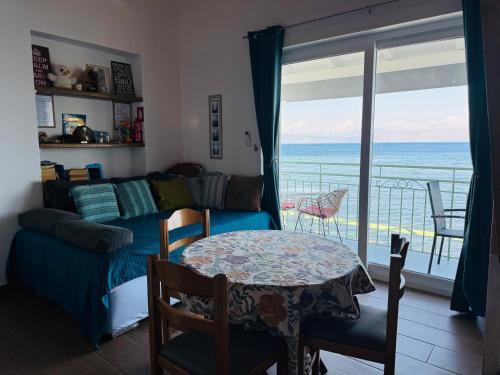 a living room with a couch and a table with a view of the ocean at Avra Benitses Beach Apartment in Benitses