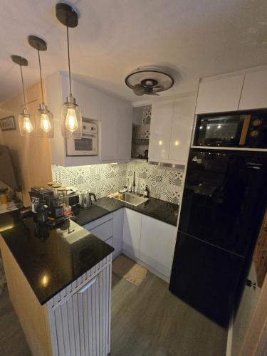 a kitchen with white cabinets and a black counter top at Zen Vibes Modern 2BR Asian Fusion Stay in Manila
