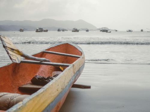 a wooden boat sitting on the shore of a beach at Tombo Beach in Guarujá