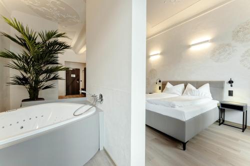 a bedroom and a bathroom with a bed and a bathtub at Aparthotel Lavilo Main Square in Graz
