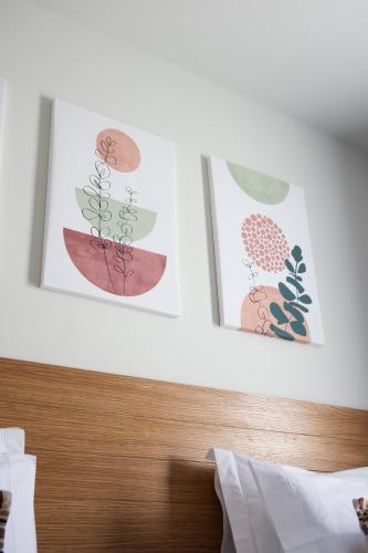 two pictures of plants on the wall above a bed at Casas do Picoto in Chaves