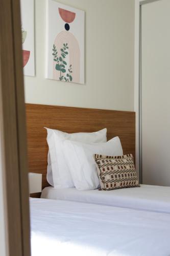 a bed with white pillows and a wooden headboard at Casas do Picoto in Chaves