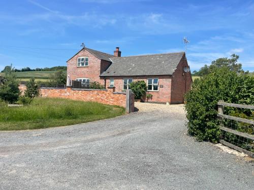 a brick house with a fence next to a road at Grooms Cottage in Leicester