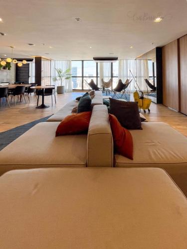 a large living room with a large couch with pillows at NOVO Skylux 1109 Imponente com Piscina Aquecida WIFI in Rio de Janeiro