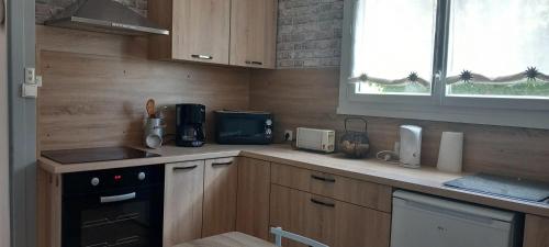 eine Küche mit Holzschränken, einem Herd und einem Fenster in der Unterkunft Maison Cosy avec Terrasse à Vallenay in Vallenay