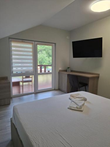 a bedroom with a bed and a flat screen tv at Pensiunea Valea Negrasului in Trăisteni