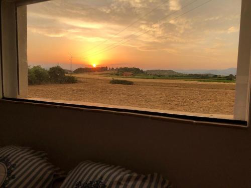 a window with a view of a field with the sunset at Duplex piscine calme in Vendémian