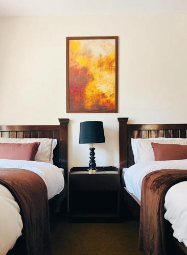 a bedroom with two beds and a lamp on a table at Soma Hotels Skardu in Skardu