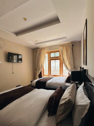 a bedroom with two beds and a window at Soma Hotels Skardu in Skardu