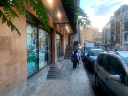 una persona che va in bicicletta lungo un marciapiede accanto a un edificio di RG Boutique Hotel a Yerevan