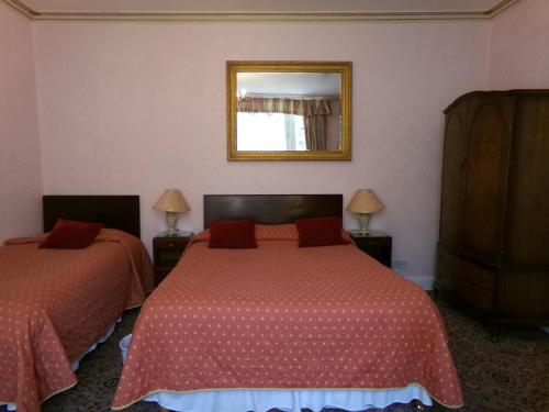a bedroom with two beds and a mirror on the wall at Averon Guest House in Edinburgh