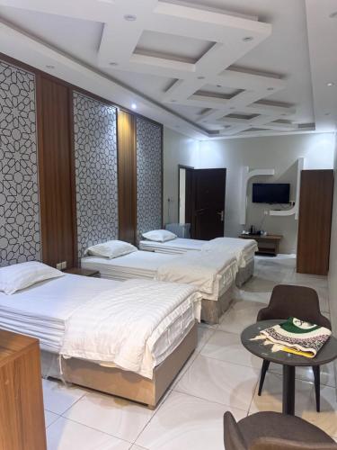 a hotel room with three beds and a tv at المحرق للشقق المخدومة in Al Hofuf
