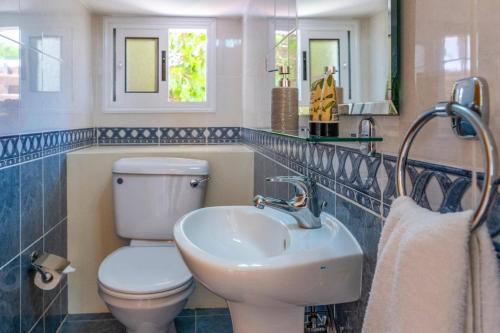 a bathroom with a white toilet and a sink at Villa Gardenia by Villa Plus in Peyia