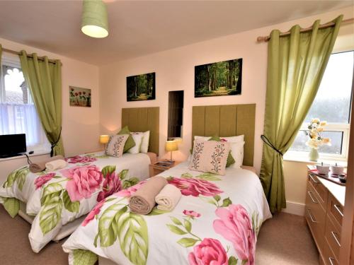 - 2 lits dans une chambre avec des rideaux verts dans l'établissement 5 Bed in Alnwick 60497, à Alnwick
