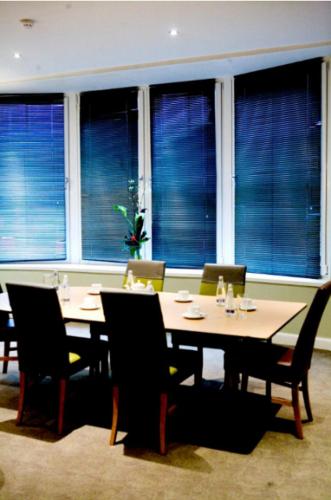 a dining room with a table and chairs and windows at Artto Hotel in Glasgow
