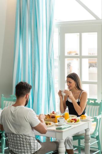 a man and woman sitting at a table eating food at Aressana Spa Hotel & Suites - Small Luxury Hotels of the World in Fira