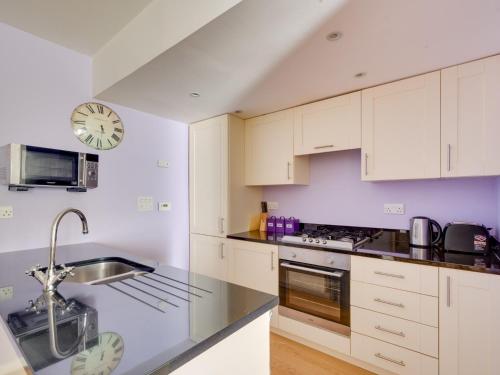 a kitchen with white cabinets and a clock on the wall at 2 Bed in Fort Augustus 80700 in Fort Augustus