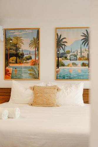 a bedroom with two paintings above a bed at Suite 1 - Les pieds dans le sable de Grand-Case, un bien nouveau et rare dans la toute nouvelle résidence Mogador in Grand Case
