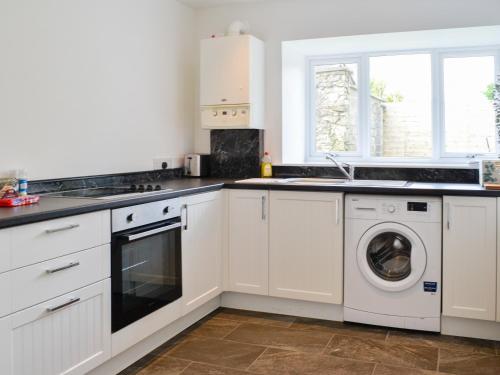 a kitchen with white cabinets and a washer and dryer at Kirroughtree Steading 2 - Uk42904 in Newton Stewart