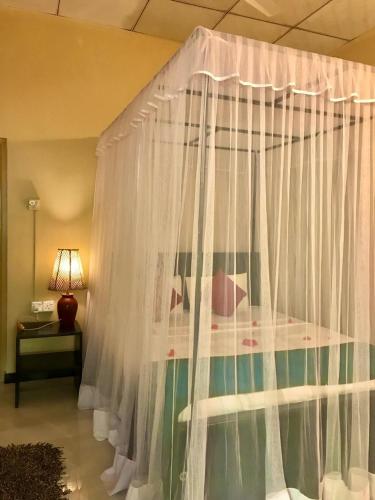 a canopy bed with white curtains in a bedroom at Green Bamboo House in Sigiriya