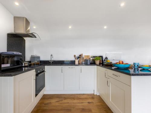 a kitchen with white cabinets and black counter tops at 1 Bed in Bude 88498 in Morwenstow