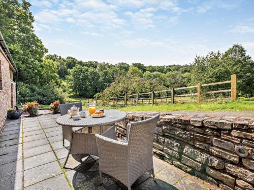 a patio with a table and chairs and a stone wall at 1 bed in Bampton LIMKC in Bampton