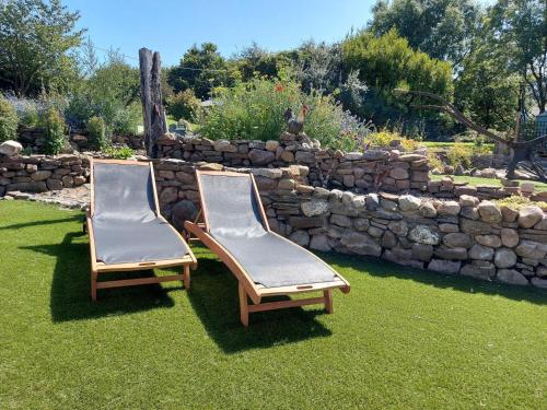 two chairs sitting on the grass in front of a stone wall at 1 bed property in Gower 77981 in Penclawdd
