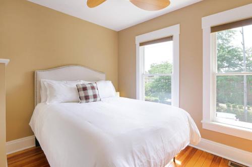 a bedroom with a white bed with two windows at Home with Garage, Hot Tub, near OSU & Short North in Columbus