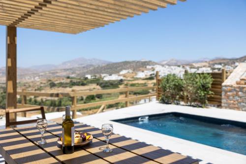 a table with wine glasses and a bottle of wine at Bonsai Luxury Villas Naxos in Naxos Chora